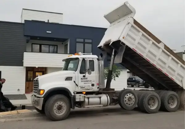 Dump truck tipping a load of fill material at a townhome complex construction site in evening light